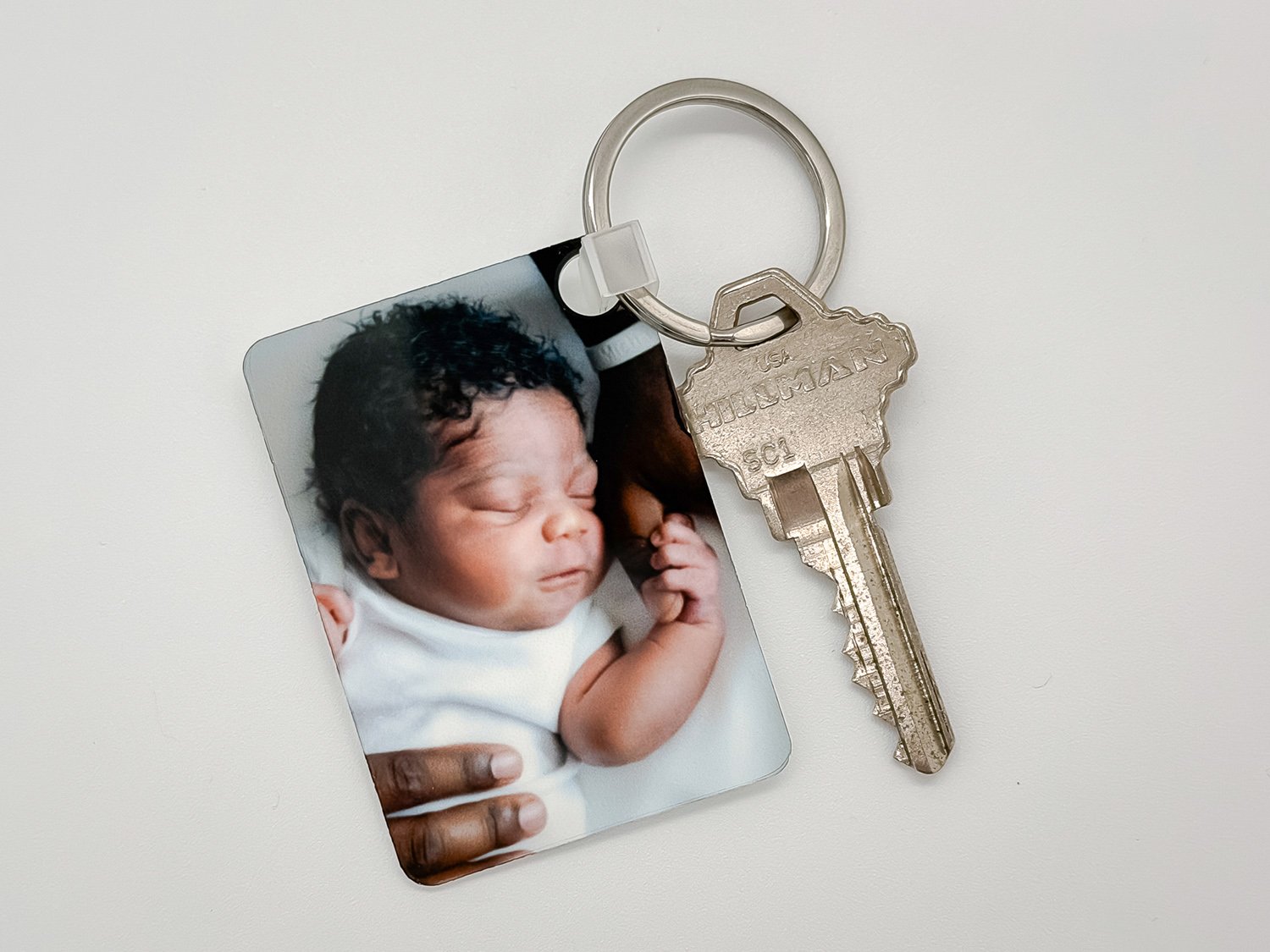 Rectangular photo keychain featuring a newborn baby holding a parent's finger.