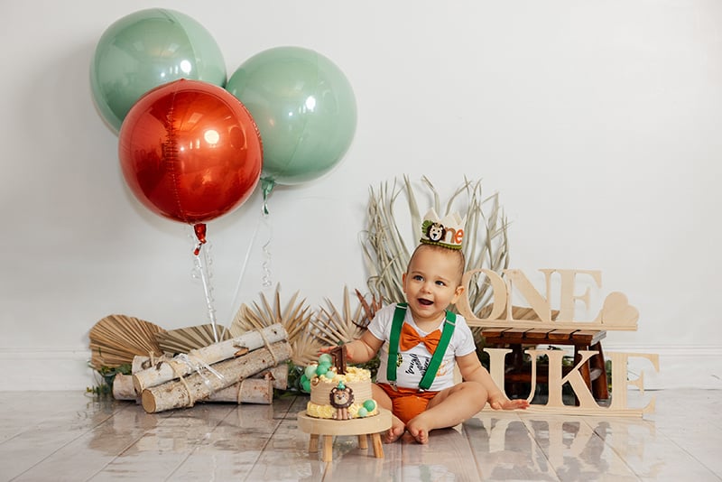 One year old boy seated with a cake for a themed milestone photoshoot