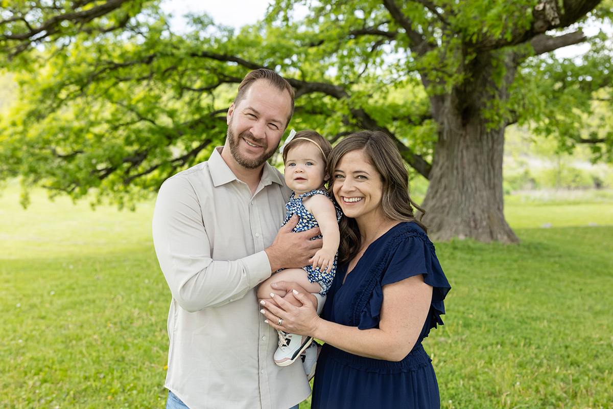 Parents in solid neutrals, one in cream and one in navy, paired with a complementary patterned dress for their baby.