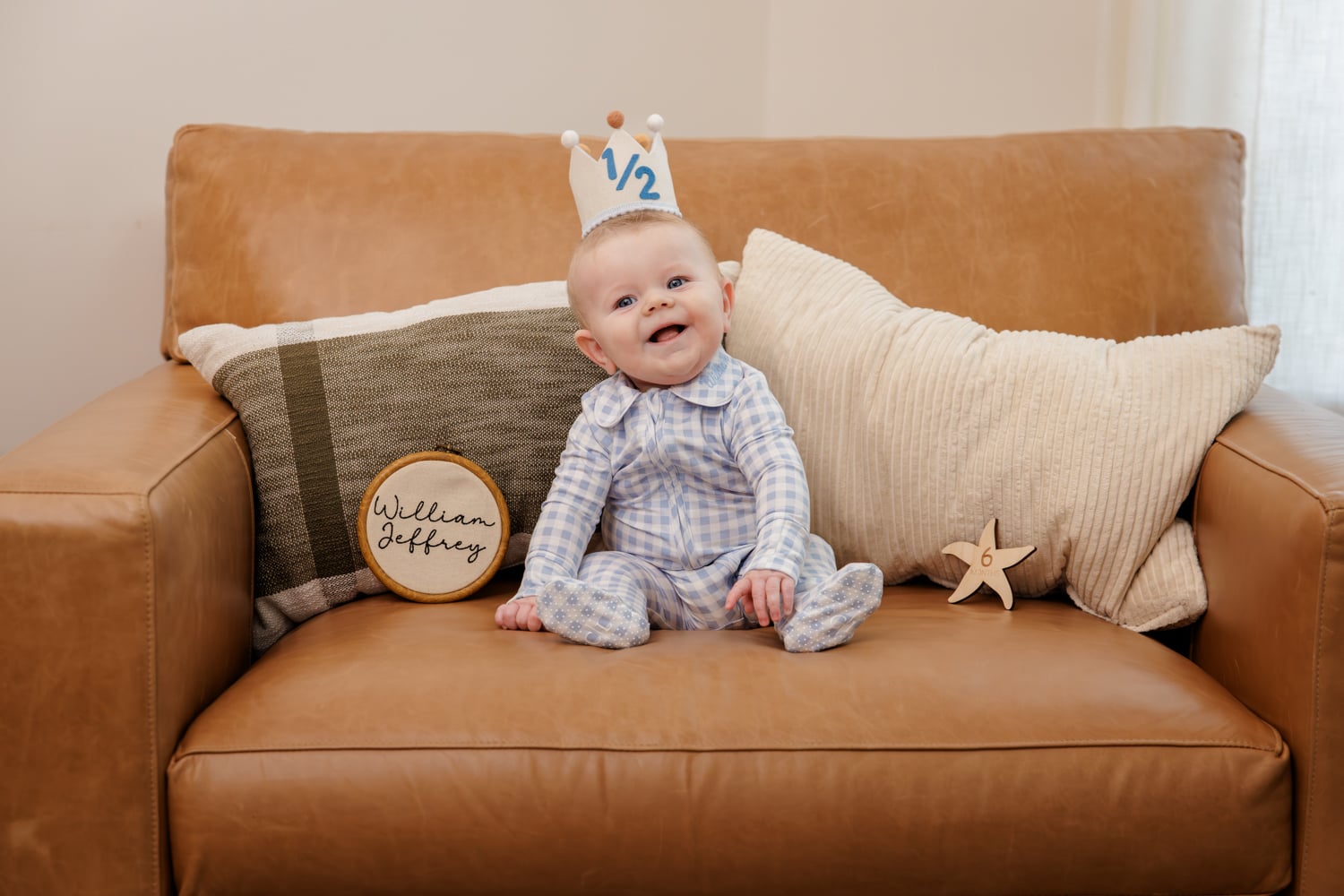 Six month old boy seated in a chair wearing a half birthday crown