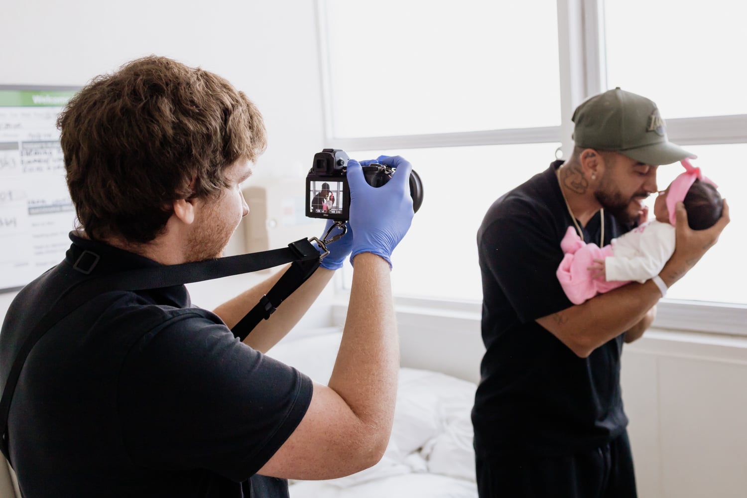 A Bella Baby photographer capturing an image of a father holding his newborn baby