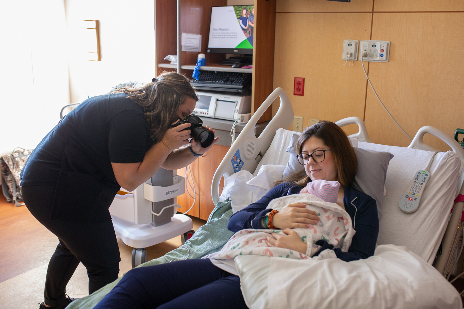 A Bella Baby photographer photographing a mother and baby in a hospital setting