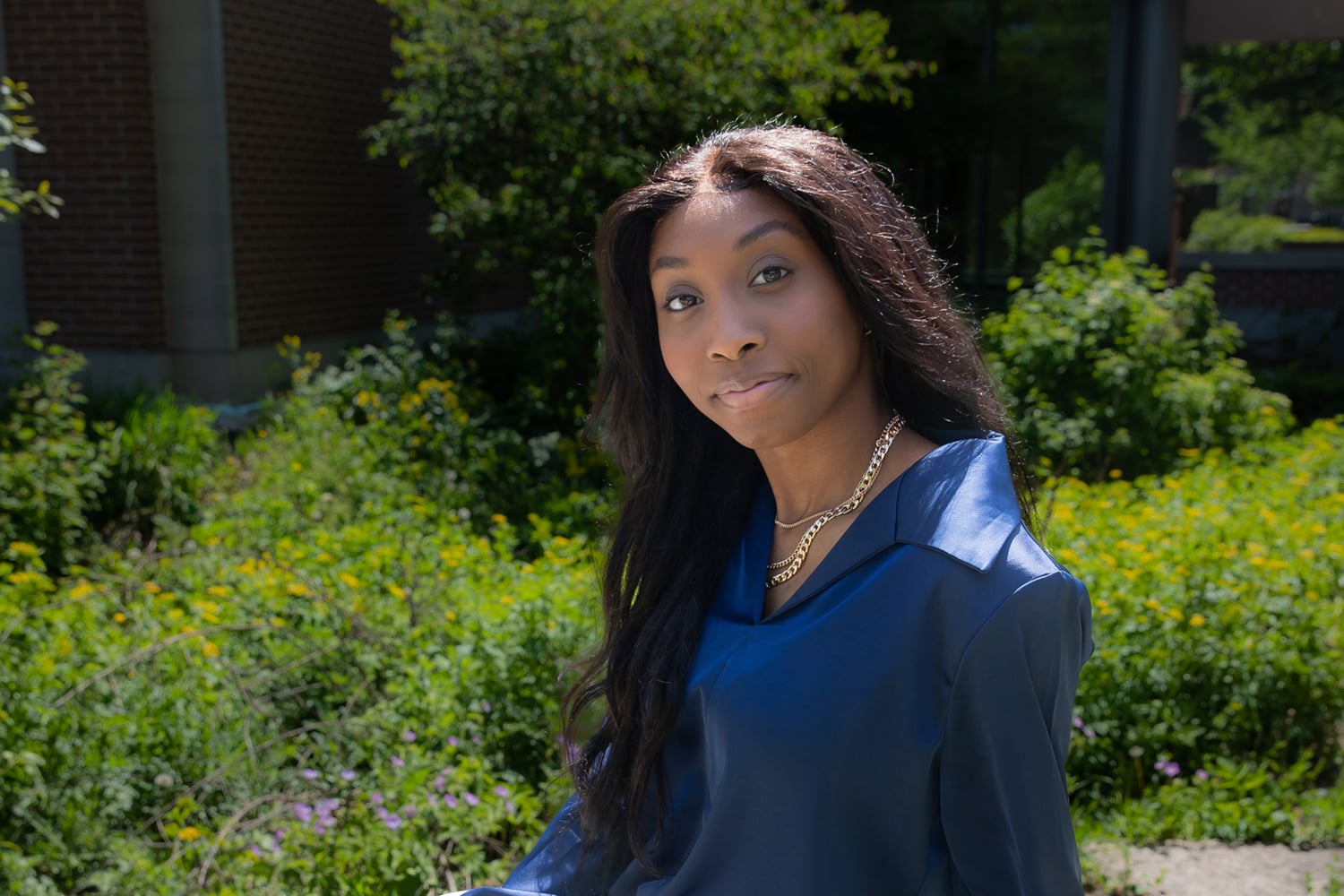 Headshot of a woman seated in front of greenery